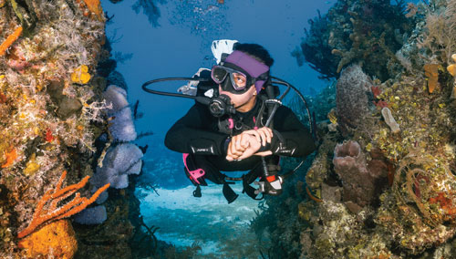 Diver in SCUBAPRO gear swimming between coral reefs
